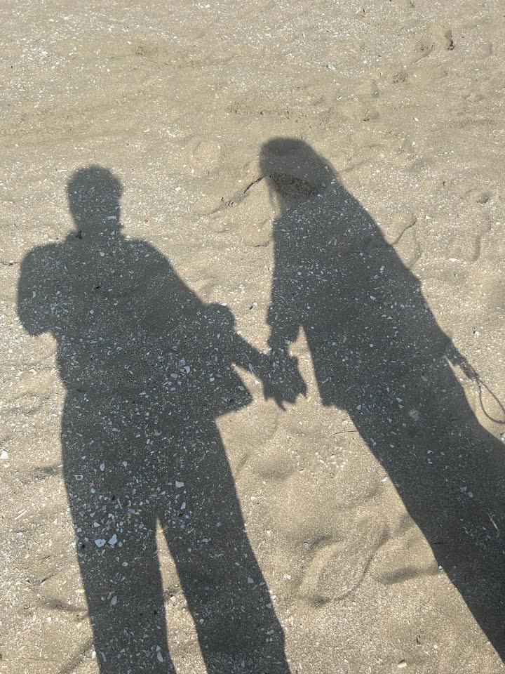 Les ombres de Dorah et Oscar, main dans la main, sur le sable