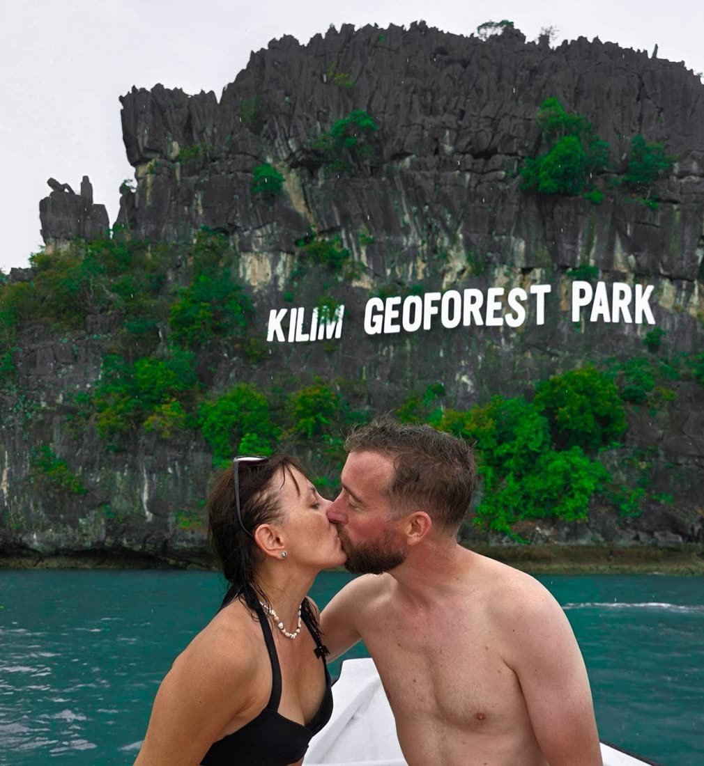 Ania et Luke s’embrassent sur un bateau devant la falaise du Kilim Geoforest Park