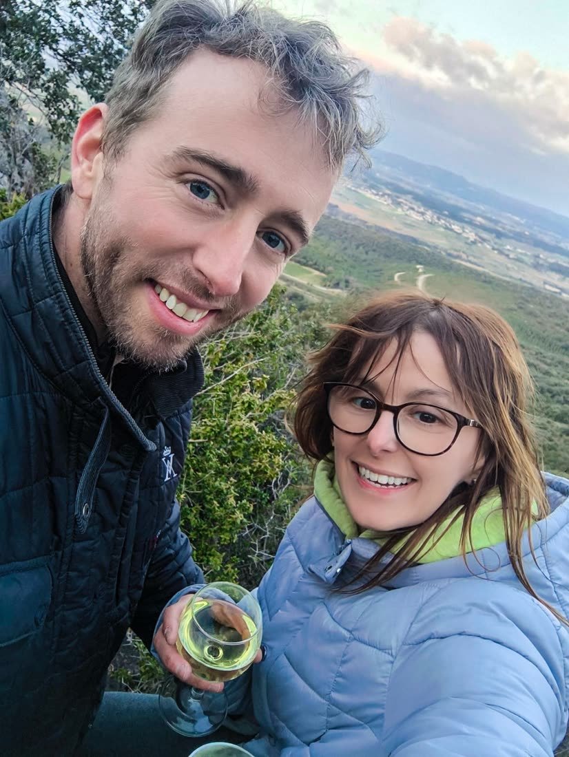 Ania et Luke, un verre de vin blanc à la main, au sommet d’une colline dominant la plaine